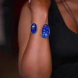 Person wearing blue oval earrings on a blurred background
