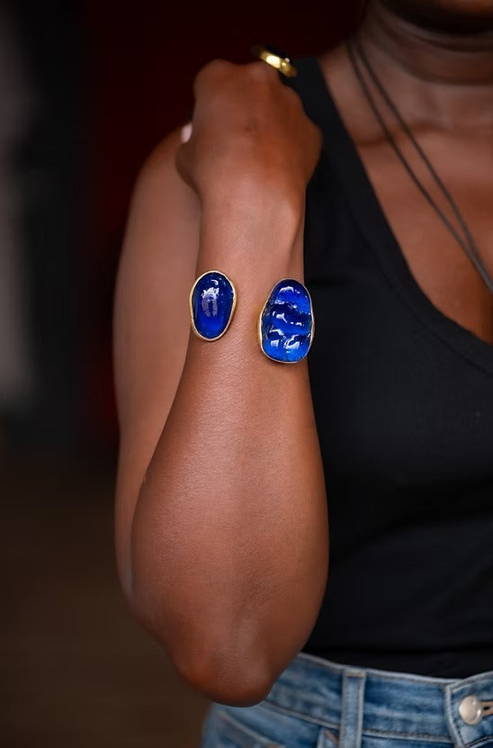 Person wearing blue oval earrings on a blurred background