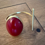 Gold bracelet with a red stone on a wooden surface