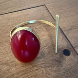 Gold bracelet with a red stone on a wooden surface