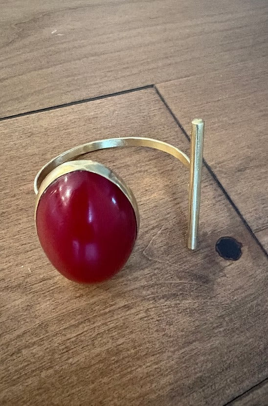 Gold bracelet with a red stone on a wooden surface
