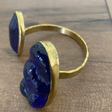Gold bracelet with blue stones on a wooden surface