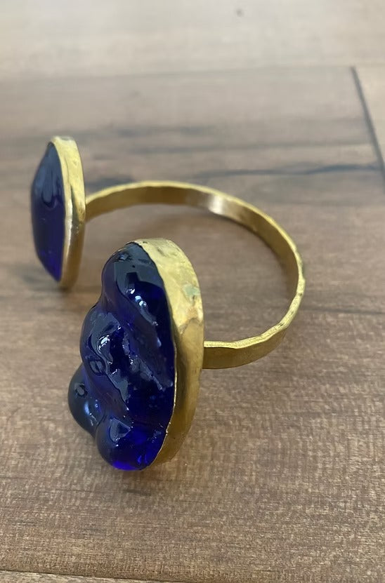 Gold bracelet with blue stones on a wooden surface
