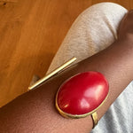 Red and gold bracelet on a wrist with a wooden floor background
