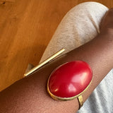 Red and gold bracelet on a wrist with a wooden floor background