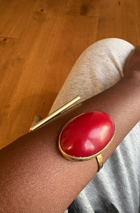 Red and gold bracelet on a wrist with a wooden floor background