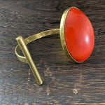 Brass ring with a red stone on a wooden surface