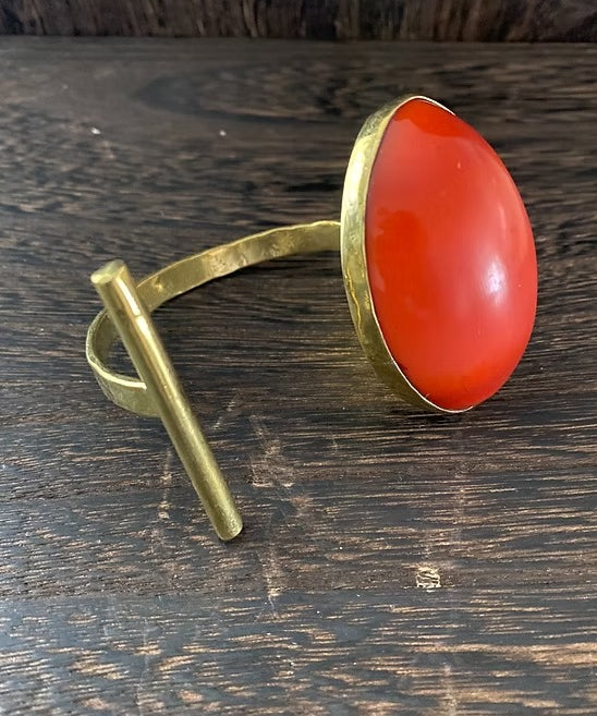 Brass ring with a red stone on a wooden surface