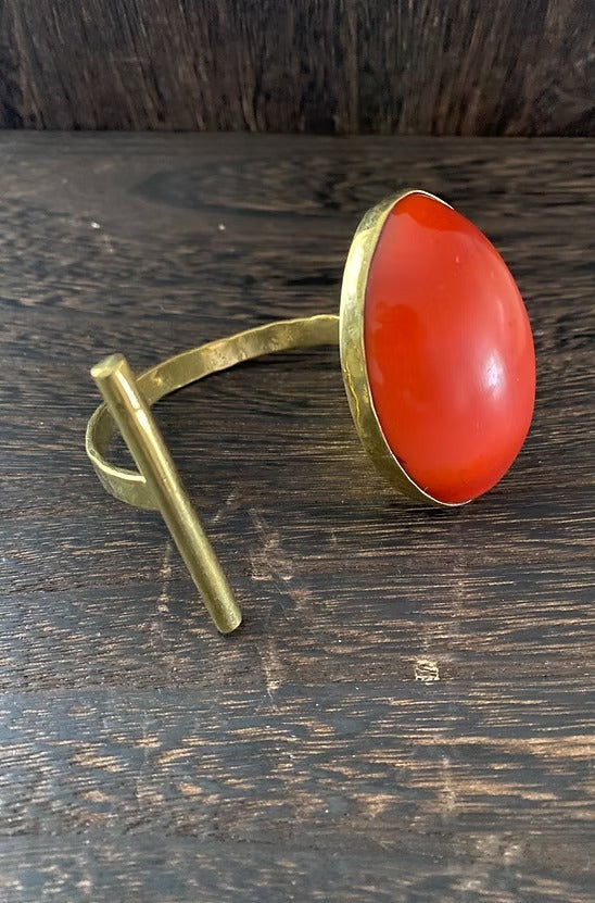 Brass ring with a red stone on a wooden surface