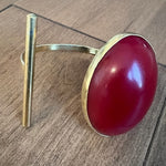 Gold ring with a red stone on a wooden surface