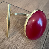Gold ring with a red stone on a wooden surface