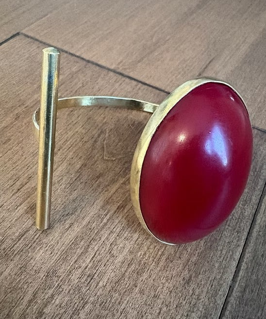 Gold ring with a red stone on a wooden surface