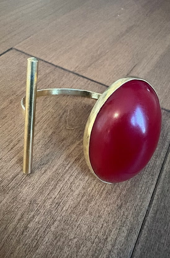 Gold ring with a red stone on a wooden surface