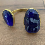Gold bracelet with blue stones on a wooden surface