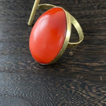 Ring with a red stone and gold band on a dark wooden surface