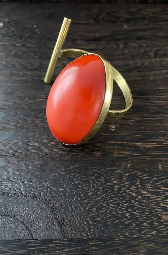 Ring with a red stone and gold band on a dark wooden surface